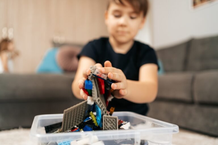 School boy playing lego at home